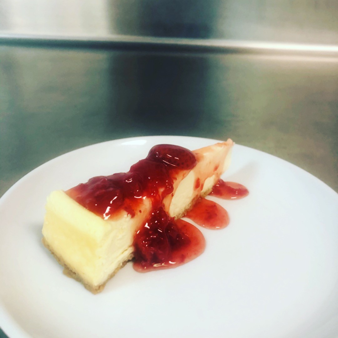 A slice of cheesecake with strawberry topping at Grecian Steak House