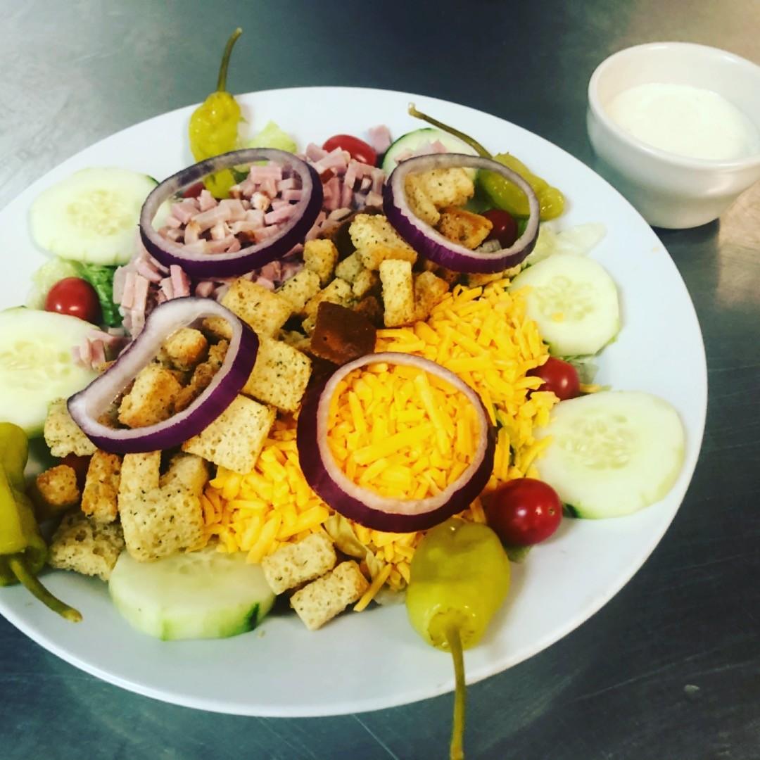 A chef salad with ham, cheese, croutons, and vegetables at Grecian Steak House