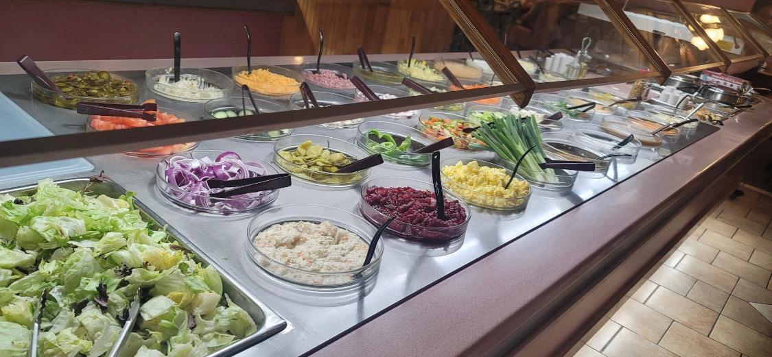 The salad bar at Grecian Steak House, fresh vegetables and toppings in individual bowls